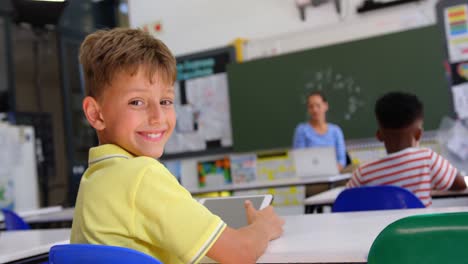 Rückansicht-Eines-Glücklichen-Kaukasischen-Schuljungen,-Der-Im-Klassenzimmer-In-Die-Kamera-Blickt,-4K