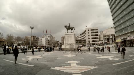 memorial of ataturk on horse  square turkish flags passersby pigeons cloudy day urban cityscape