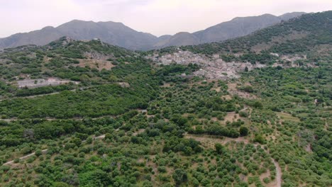 Aerial-showing-beautiful-green-mountains-with-curved-roads-under-cloudy-sky,-wanderlust-and-travelling