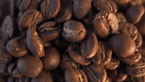 up close macro view of freshly roasted, brown coffee beans in warm light to be used for hot, black coffee rotating left