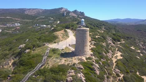 toma aérea de un faro en la costa de cádiz, al sur de españa, con una pasarela y las montañas detrás en un día soleado