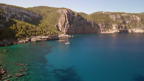 Velero-Blanco-Navega-Hacia-La-Bahía-Solitaria-Secreta-En-Ibiza