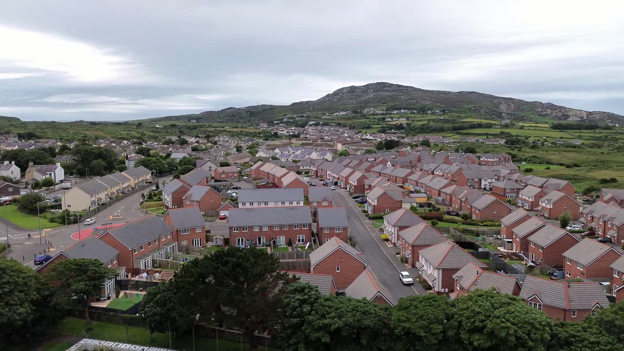 Aerial view establishing modern red brick housing neighbourhood under Holyhead mountain in Wales