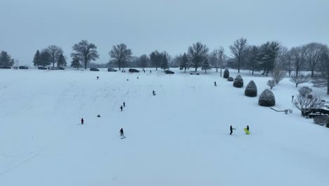 aerial view of kids sledding on snowy winter hill in usa