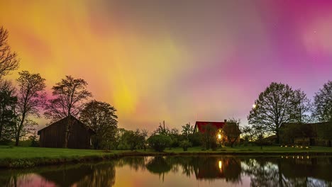 colorido aurora boreal cielo timelapse en un lago reflectante con casas de granja