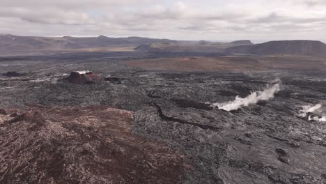 aerial view of a volcanic crater and steaming fissure in a rugged lava field in iceland.