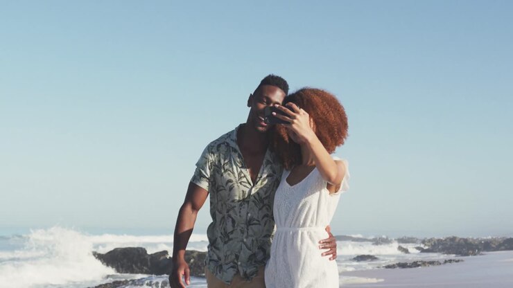 African American couple taking a selfie seaside