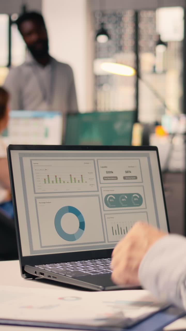 Vertical Video Worker analyzes business intelligence and monetary data on laptop