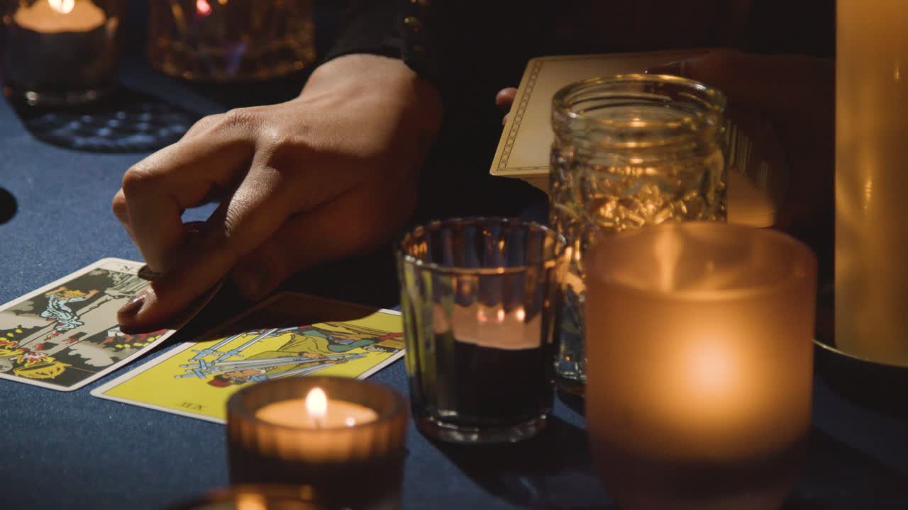 un primer plano de una mujer dando una lectura de tarot en la mesa 2 a la luz de las velas.
