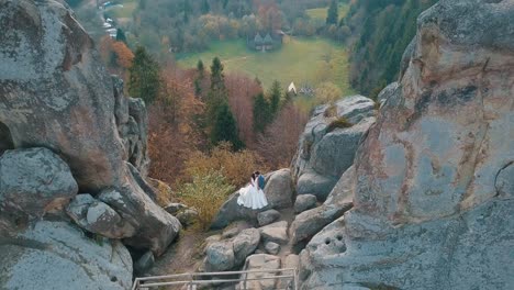 Newlyweds-stand-on-a-high-slope-of-the-mountain.-Groom-and-bride.-Arial-view