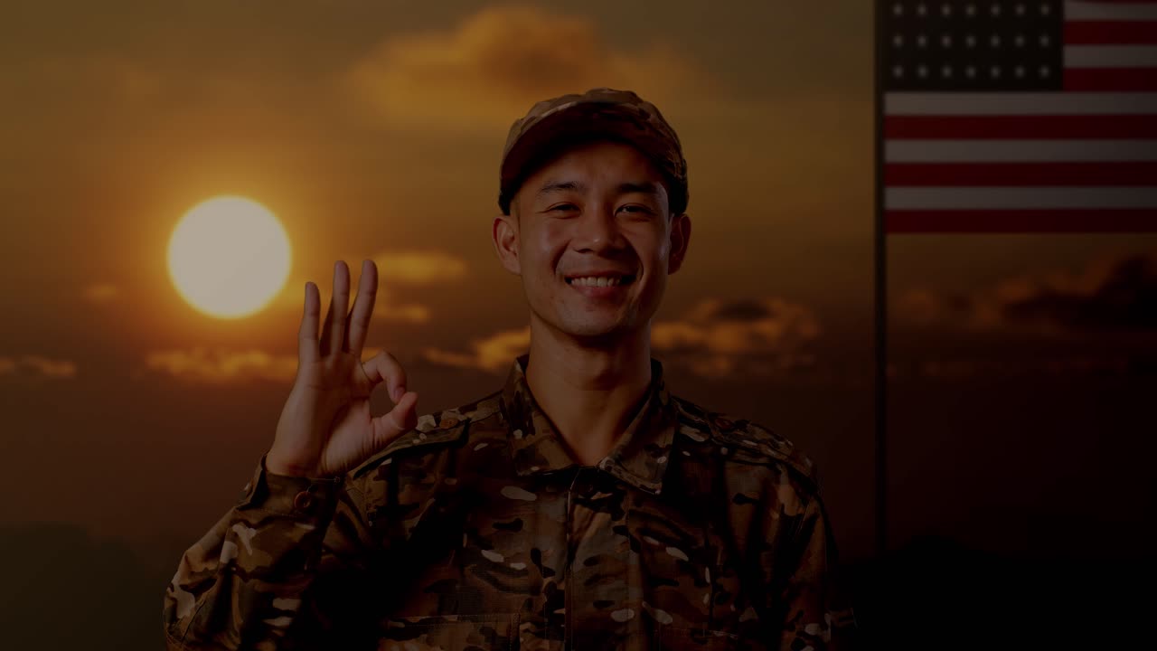아시아 남성 군인이 미소 짓고 미국 발을 들고 서있는 동안 카메라에 ok 제스처를 보여줍니다.