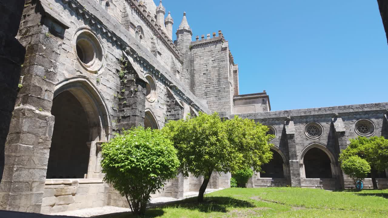 Stone arch cloister and green trees inside cathedral courtyard in évora portugal