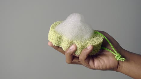 hand holding a green sponge with soap foam