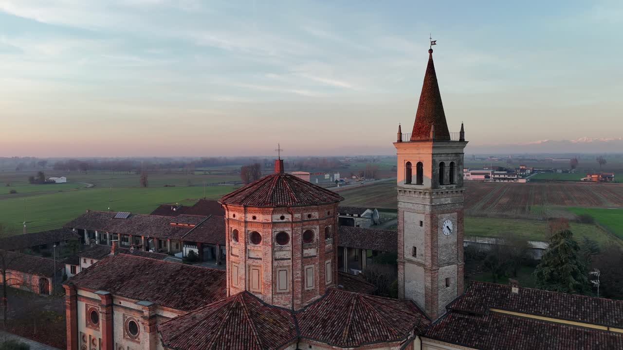 Vista aerea del Santuario della Beata Vergine della Misericordia accanto alla Strada Paullese Strada Provinciale SP 415 fino alla rotonda di Milano, strada moderna che attraversa i campi rurali lombardi al tramonto