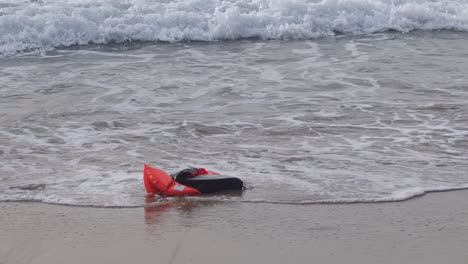 empty life jacket washes ashore beach, slow motion