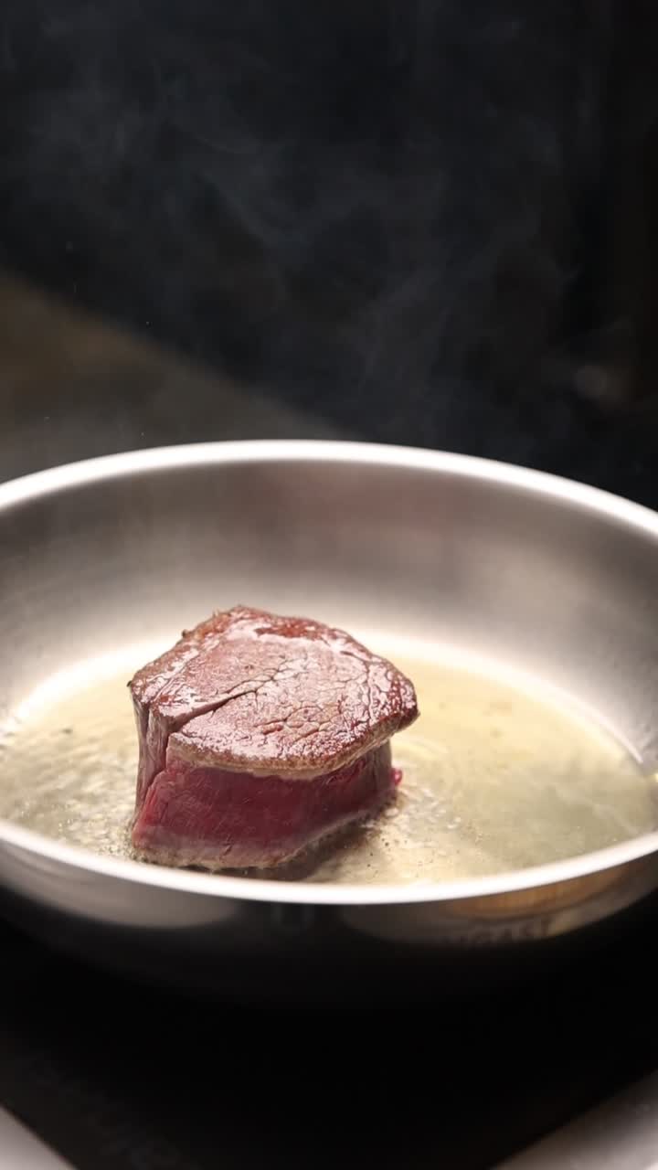 Chef che rosola uno spesso taglio di bistecca in una padella calda