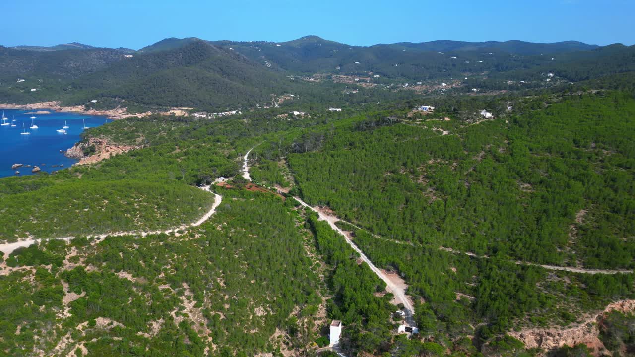 Ibiza Bays and green vally Hills, Spain, overlooking a picturesque bay with turquoise water and boats sailing on a sunny summer day. Perfect aerial view flight panorama overview drone