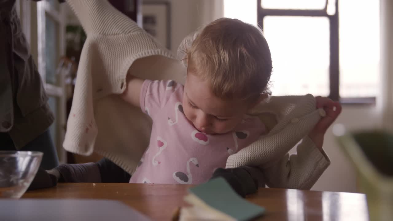 Caucasian woman undressing baby at home