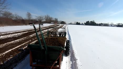 agricultural machinery is being pulled to spread manure on farmland during sunny winter day