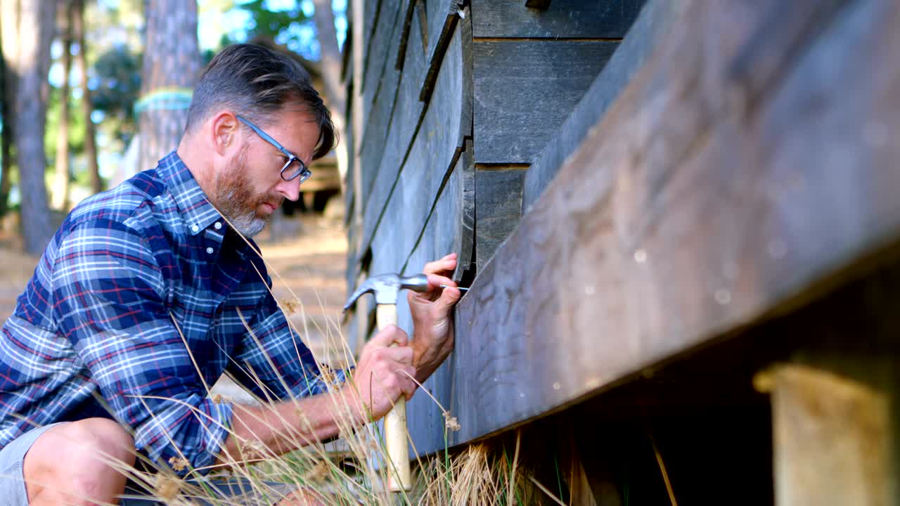 Man hammering wooden plank with hammer 4k