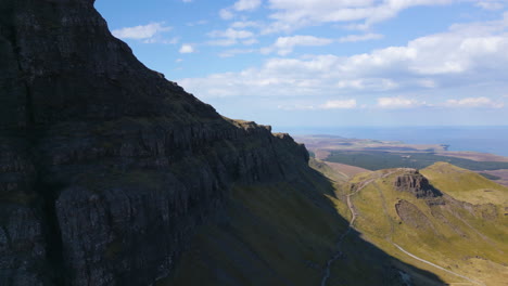 Aerial-flying-forward-to-hiking-viewpoint-Old-Man-of-Storr,-Scotland