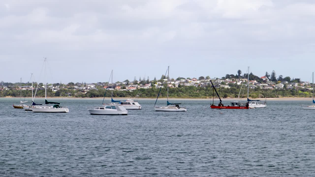 바람이 불고 구름이 많은 날 뉴질랜드 오클랜드의 배경에 이웃이 있는 호수에서 떠다니는 몇 대의 배의 드
