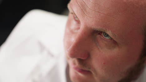 a close-up view of a technician on white lab coat and black gloves resting his head on his left arm, showcasing a moment of fatigue