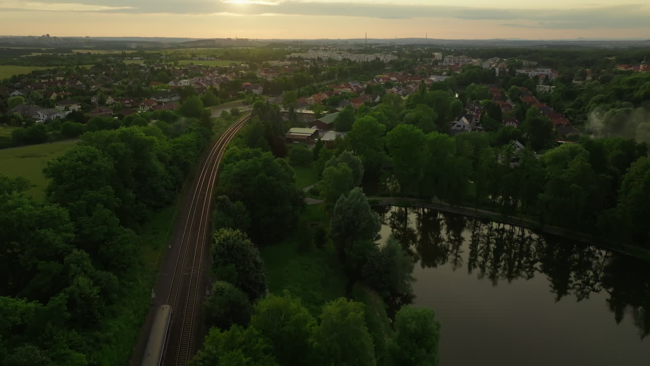 해가 지는 동안 교외 지역 을 지나가는 열차 의 공중 사진