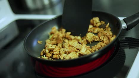 slow motion shot of someone cooking sizzling chicken in a pan over a stove