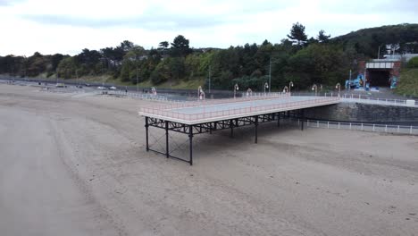 Colwyn-Bay-Welsh-Seaside-Town-Pier-Boardwalk-Vista-Aérea-Sobre-Moody-Nublado-Arena-Marea-Baja-Playa-órbita-Izquierda