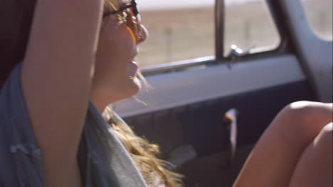 beautiful woman enjoying ride in convertible vintage car on road trip with outstretched arms