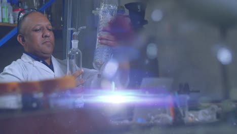 animation of glowing light over biracial man working in laboratory workshop