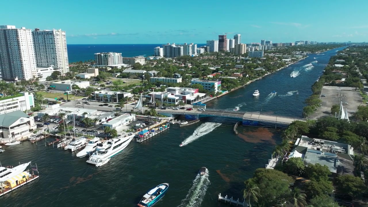 Riprese con drone della vivace Intracoastal a Pompano Beach, dove gli yacht navigano sotto un ponte trafficato e il calmo canale blu si estende verso l'orizzonte atlantico.