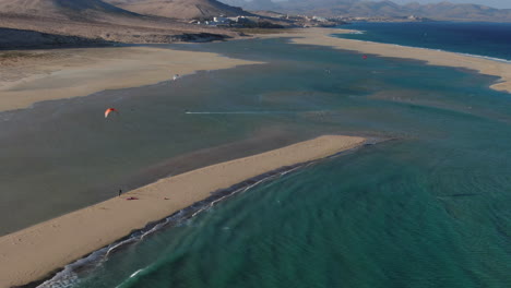 Playa-De-La-Barca,-Fuerteventura:-Vista-Aérea-En-órbita-Sobre-Personas-Practicando-Kitesurf-Cerca-De-La-Orilla