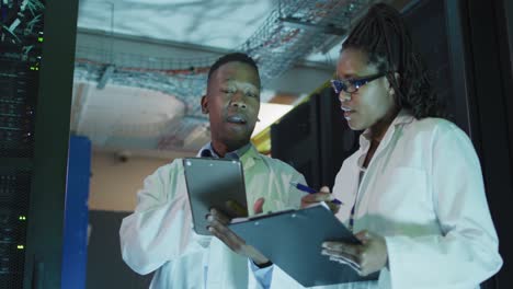 african american computer technicians using tablet working in business server room