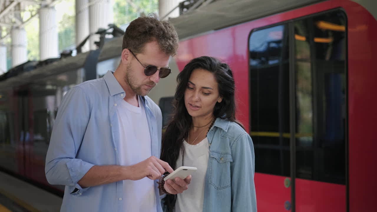 pareja mirando un teléfono inteligente en la estación de tren