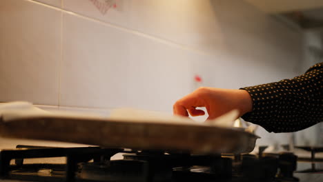 a woman hands are turning hot cookies in the pan out of the oven