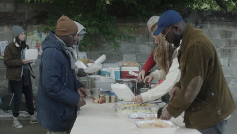volunteers distribute food to people in need outdoors