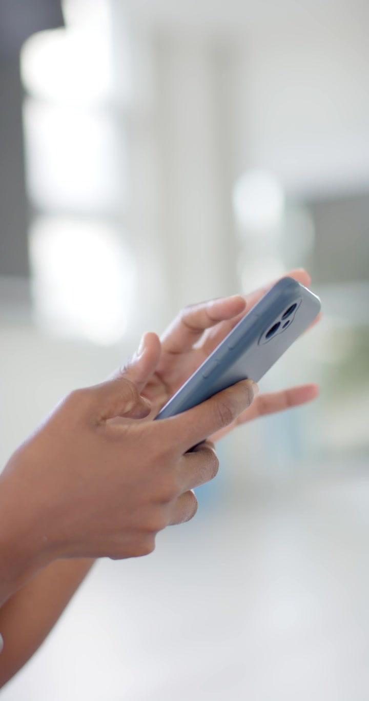 Video verticale: Donna afroamericana che entra, tocca il telefono blu, controlla i messaggi a casa e guarda l'orologio.