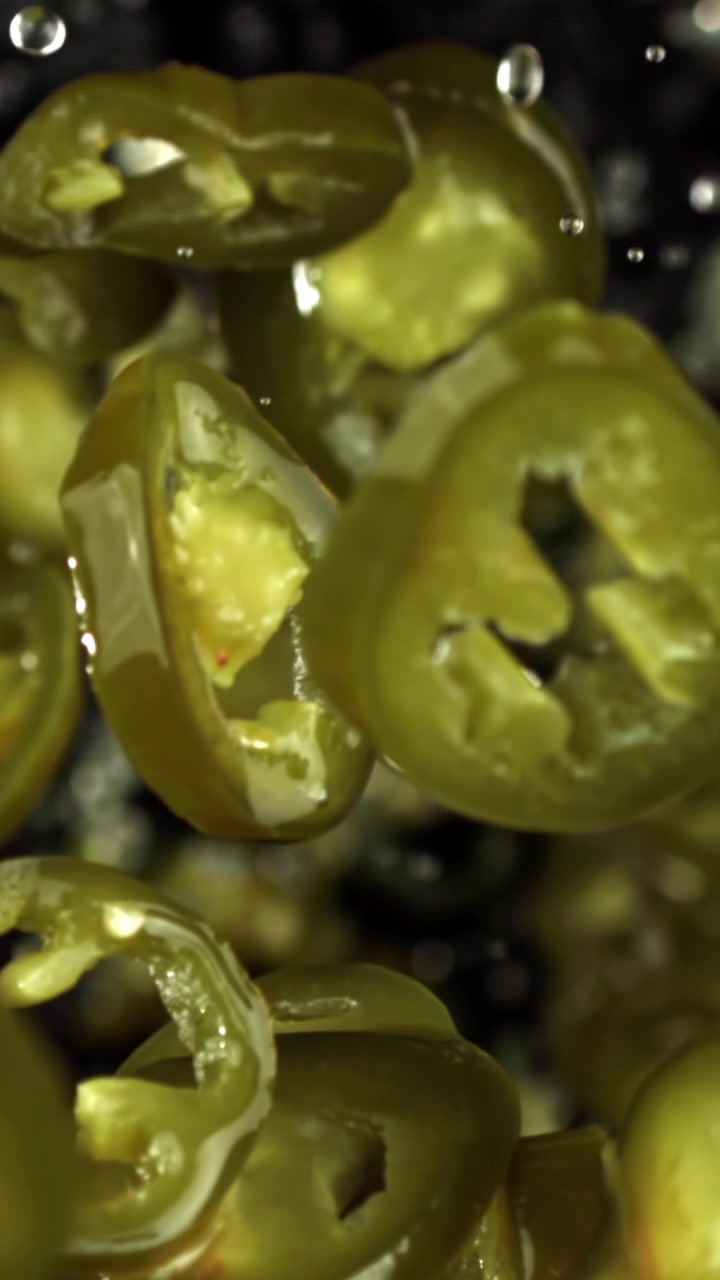 Close-up de Fatias de Pimenta Jalapeño Verde Fresca Salpicando Água em Câmera Lenta