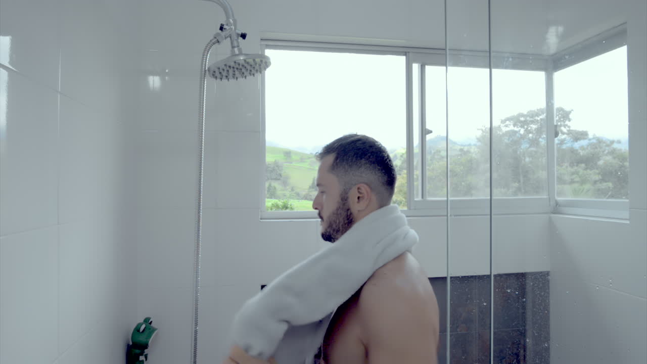 MAN IN THE SHOWER DRYING WITH A TOWEL WHILE HE LOOKS THROUGH THE WINDOW  MOUNTAIN SIDE LUXURY PROPERTY