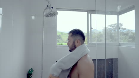 man in the shower drying with a towel while he looks through the window  mountain side luxury property