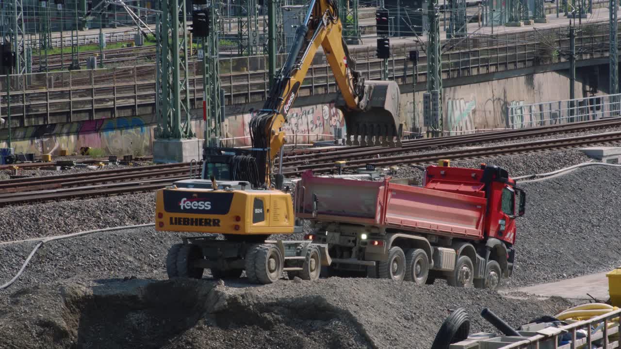 Excavator digging and loading gravel in truck in front of railways Stuttgart 21