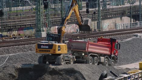excavator digging and loading gravel in truck in front of railways stuttgart 21