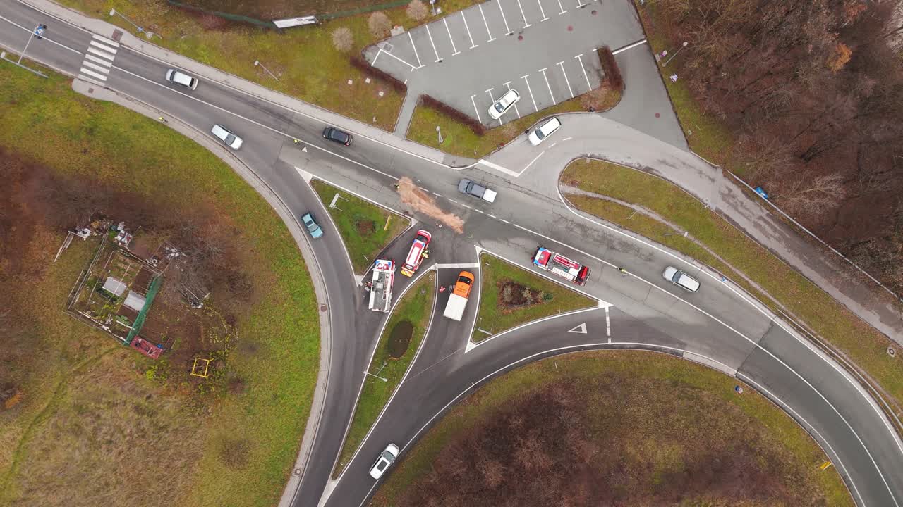 Firefighters clean an oil spill after a crash at a busy intersection, top down drone view