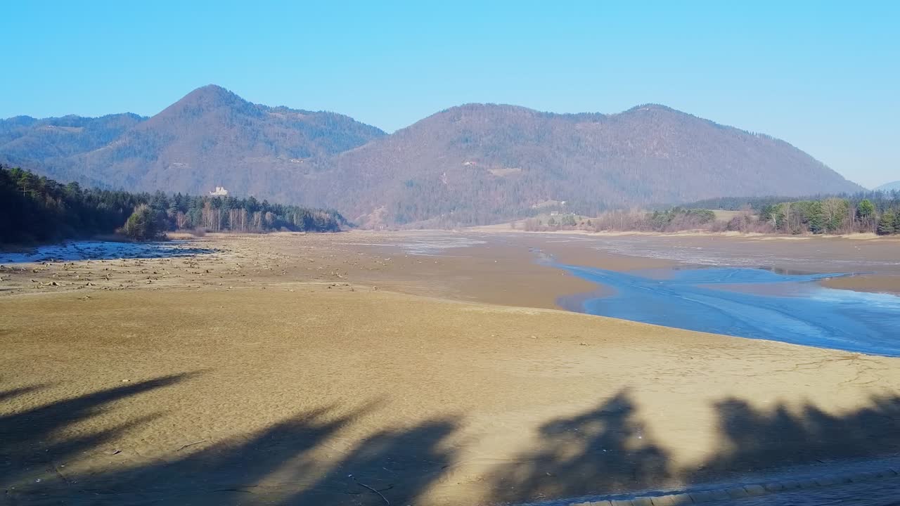 Aerial view of the beautiful dry golden lake with mountains on the background. Slovenia