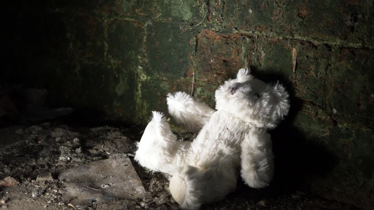 osito de peluche de un niño descartado en el sótano de un edificio antiguo. toma panorámica media.