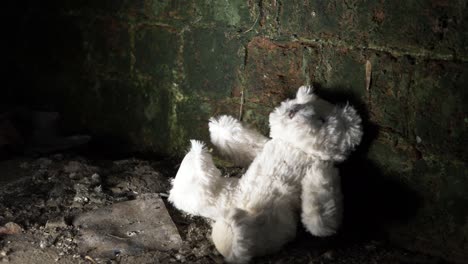 child's teddy bear discarded in old building basement medium panning shot