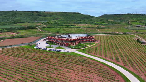 orbiting aerial view of a modern winery surrounded by green vineyards in la rioja, spain. scenic agricultural landscape, perfect viticulture setting in renowned wine region