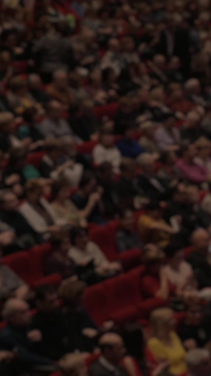 Pubblico sfocato che applaude in un auditorium.